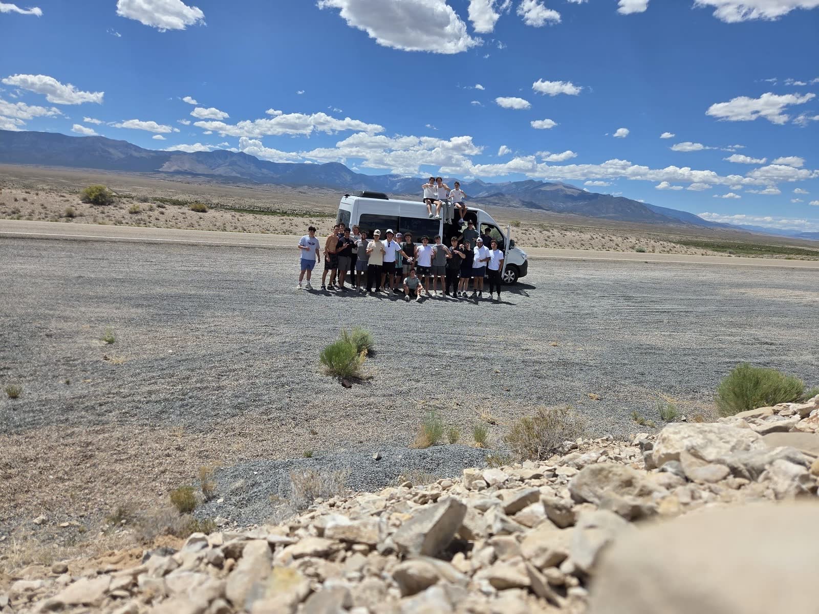 Camp Shepsala group beside a van in a desert mountain landscape
